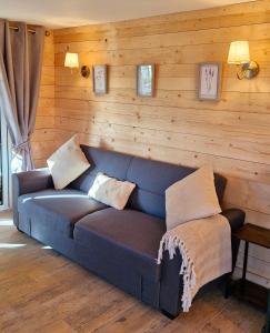 a blue couch in a room with a wooden wall at Cozies Cabin in Billy