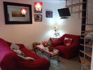 una sala de estar con 2 sofás rojos y una mesa. en La petite maison dans la prairie, en Notre-Dame-du-Touchet