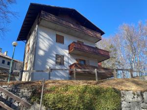 um edifício com uma varanda no topo de uma colina em Casetta nel bosco - Appartamento "Le betulle" Lavarone em Chiesa