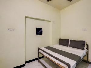 a small bed in a room with white walls at SPOT ON Hotel Ik Recedency in Chandrapur