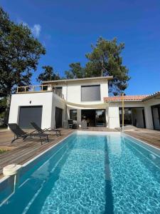 a house with a swimming pool in front of a house at Villa confort piscine chauffée*/10KM CONTIS Plage in Lit-et-Mixe