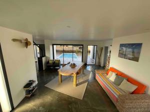 a living room with a table and a couch at Villa confort piscine chauffée*/10KM CONTIS Plage in Lit-et-Mixe