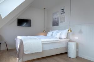 una camera bianca con un grande letto con lenzuola bianche di Haus Grüne Düne a Wenningstedt