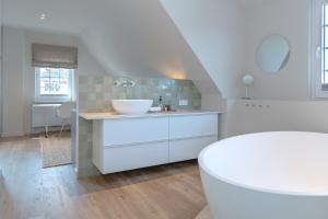 een witte badkamer met een wastafel en een aanrecht bij Haus Grüne Düne in Wenningstedt