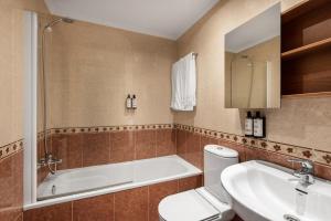 a bathroom with a tub and a toilet and a sink at Apartamentos El Cid in Burgos