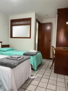 a room with two beds and a table and a podium at Apartamento em frente a praia Costa 1001 in Vila Velha