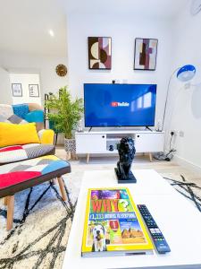 uma sala de estar com uma televisão e uma mesa de centro em FULLY FURNISHED 2 BED 1 BATH APARTMENT IN LONDON, FREE PARKING, CLOSE TO WEMBLEY STADIUM & LESS THAN 30 MiNS DRIVE TO CENTRAL LONDON em Golders Green