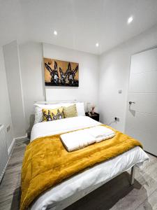 um quarto com uma cama grande com um cobertor amarelo em FULLY FURNISHED 2 BED 1 BATH APARTMENT IN LONDON, FREE PARKING, CLOSE TO WEMBLEY STADIUM & LESS THAN 30 MiNS DRIVE TO CENTRAL LONDON em Golders Green