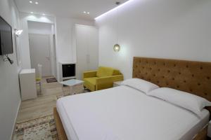 een slaapkamer met een wit bed en een gele stoel bij Elena Hotel in Sarandë