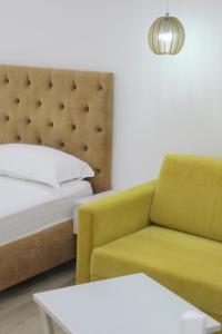 een slaapkamer met een bed, een bank en een tafel bij Elena Hotel in Sarandë