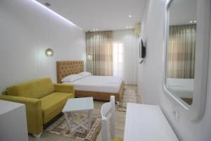 una camera con letto, divano e sedia di Elena Hotel a Sarandë