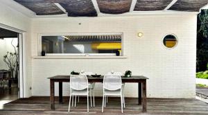 una mesa de comedor con 3 sillas blancas alrededor en Holibai, Vila Panxon, Diseño, Elegancia Y Confort Cerca Del Mar, en Nigrán