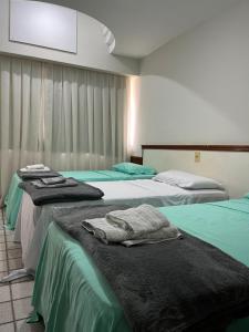 a hotel room with three beds with towels on them at Apartamento em frente a praia Costa 1001 in Vila Velha
