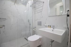 a white bathroom with a toilet and a sink at Elena Hotel in Sarandë