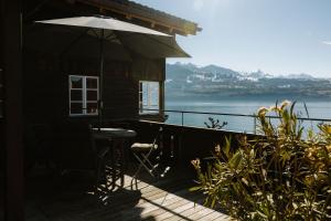 d'une terrasse avec un parasol et une vue sur l'eau. dans l'établissement Bijou Beatus - Lakeview Sunset Retreat, à Merligen