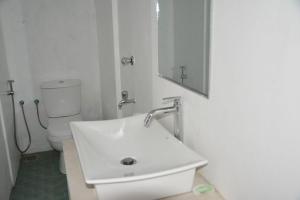 a white bathroom with a sink and a toilet at Mereiyans Village Villa in Ampara