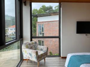 a bedroom with a chair and a large window at Homestay ECO MAY5 TRAVEL in Ha Long