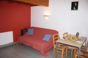 a bedroom with a red bed and a table with a tableablish at Chalets Moulière Evasion in Montamisé