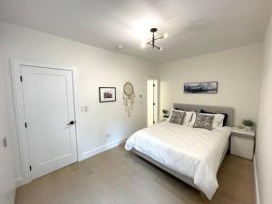 a white bedroom with a bed and a ceiling fan at Modern Apartment Close To The Beach with Parking in Toronto