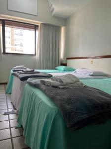 2 Betten in einem Zimmer mit Handtüchern darauf in der Unterkunft Apartamento em frente a praia Costa 1001 in Vila Velha