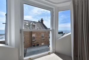 an open window with a view of a building at Penthouse on the Harbour - Pittenweem in Pittenweem