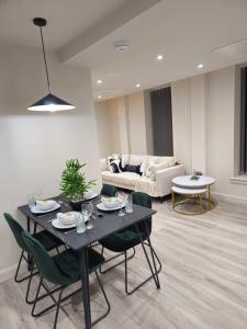 ein Wohnzimmer mit einem Tisch, Stühlen und einem Sofa in der Unterkunft Luxury Serviced Penthouse - City Centre - En Suite Bedrooms - Free Netflix in Leeds