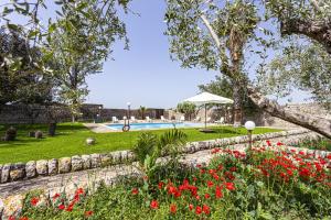un jardín con flores rojas y una piscina en Villa Concetta by Villa Plus, en Módica