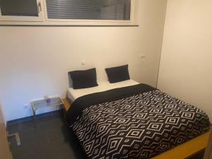 a small bedroom with a bed with black and white sheets at Cloche d'or in Luxembourg