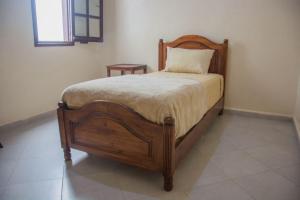 una camera con letto in legno e cuscino di HOTEL TIZNIT AFOULKI a Tiznit