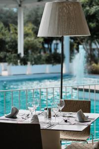 a table with wine glasses and a lamp next to a pool at Prinsotel La Dorada & Spa in Playa de Muro