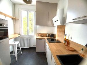 eine Küche mit weißen Schränken, einem Waschbecken und einem Fenster in der Unterkunft Fanfrelin joli T3 centre ville in Angoulême