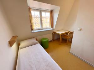 Habitación pequeña con cama, mesa y ventana en Jugendherberge Lübeck Altstadt, en Lübeck