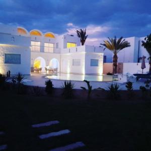 ein großes weißes Haus mit Palmen davor in der Unterkunft Villa La Palmeraie d'Arkou, grande piscine in Arkou