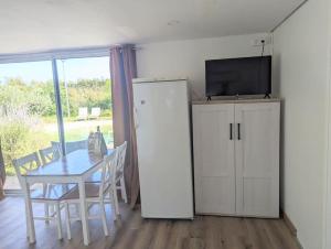 ein Esszimmer mit einem Tisch und einem TV auf dem Kühlschrank in der Unterkunft Chalet climatisé en campagne avec baignade privée in Lagnes