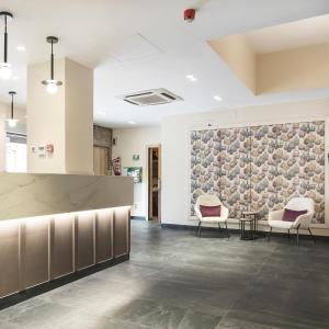 a lobby with two chairs and a stone wall at Hotel El Águila in Utebo