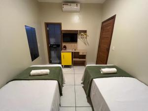 Duas camas num quarto com uma secretária e uma televisão. em POUSADA AMORIM em Santo Amaro
