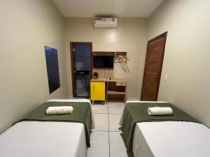 um quarto com duas camas e uma secretária em POUSADA AMORIM em Santo Amaro