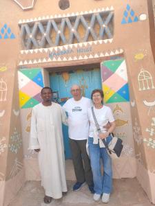 a group of three people standing in front of a house at Kabara Nubian House in Abu Simbel