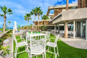 a patio with white chairs and tables on the grass at Stunning Sunsets Abama in Playa de San Juan