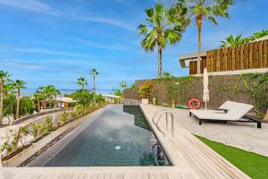 a villa with a swimming pool and palm trees at Stunning Sunsets Abama in Playa de San Juan
