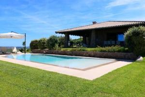 - une piscine avec un parasol en face d'une maison dans l'établissement Villa Supramonte luxury villa IUN R7796, à Marazzino