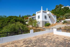 une église blanche avec une cloche au sommet d'une colline dans l'établissement Villa Jacaranda Bordeira, à Corotelo