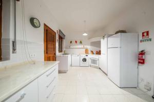 cocina con electrodomésticos blancos y nevera blanca en Villa Jacaranda Bordeira, en Corotelo