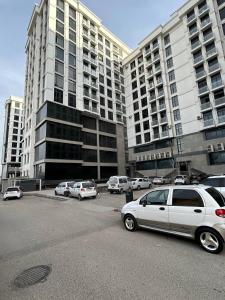un aparcamiento con coches estacionados frente a grandes edificios en Apartment for tourists en Samarcanda