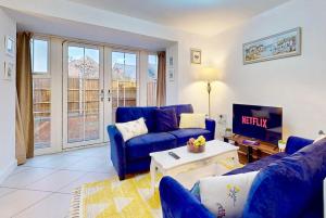 een woonkamer met blauwe banken en een tv bij Dale House, Spacious Home in Central Dartford with Parking in Kent
