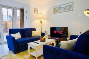 sala de estar con sofás azules y TV en Dale House, Spacious Home in Central Dartford with Parking, en Kent