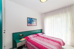 ビビオーネにあるResidence Pinewoodのベッドルーム(緑のベッド、ピンクの毛布付)