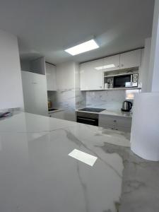 - une cuisine avec des placards blancs et un comptoir en marbre dans l'établissement Skol 925A by Completely Marbella, à Marbella