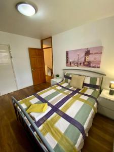 a bedroom with a bed with a striped comforter at 3 Bedroom House-Garden-Stratford-Olympic Park in London