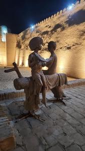 a statue of two children sitting on a bench at Ulli Oy Hotel & Terrace in Khiva